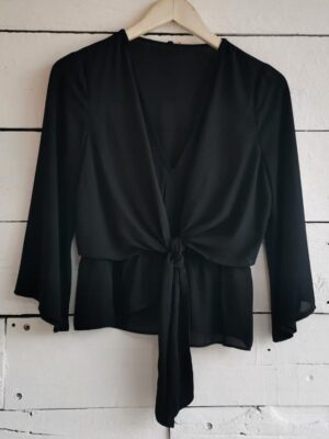 Blusa negra manga 3/4 con amarre al frente. Escote V y corte tipo peplum.