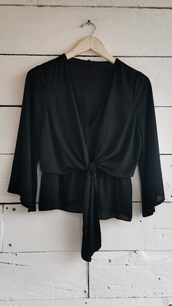 Blusa negra manga 3/4 con amarre al frente. Escote V y corte tipo peplum.