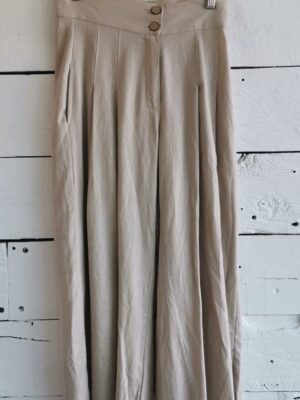 Pantalón tipo culotte beige de lino, con botones de madera y bolsas en costados.