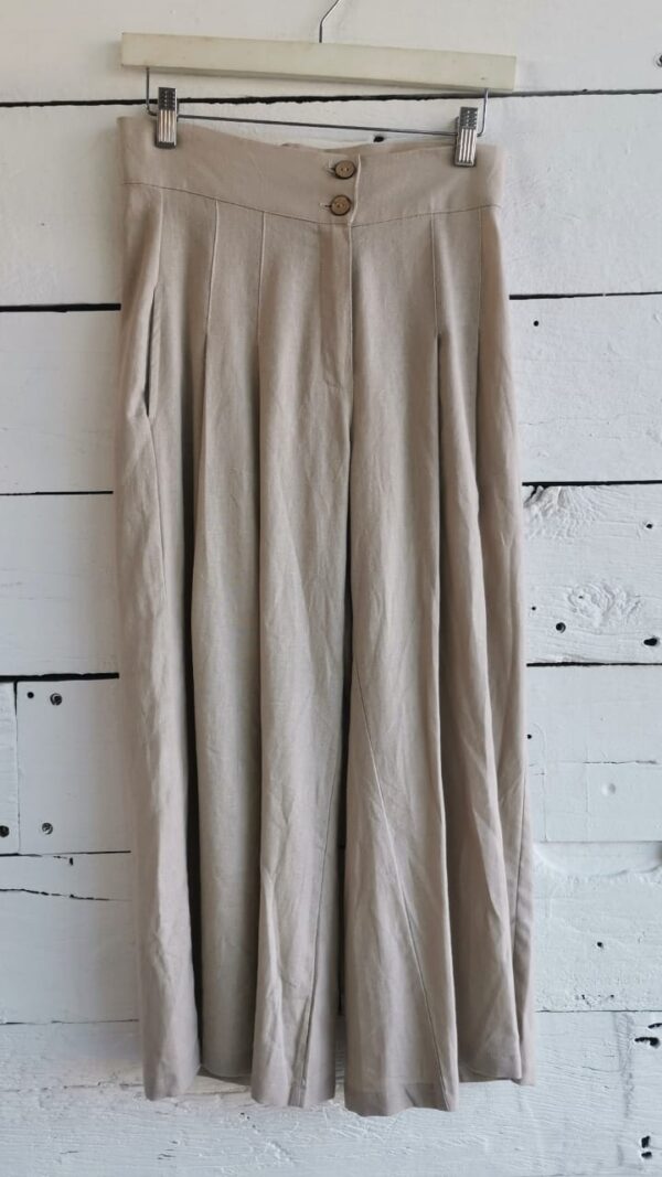 Pantalón tipo culotte beige de lino, con botones de madera y bolsas en costados.